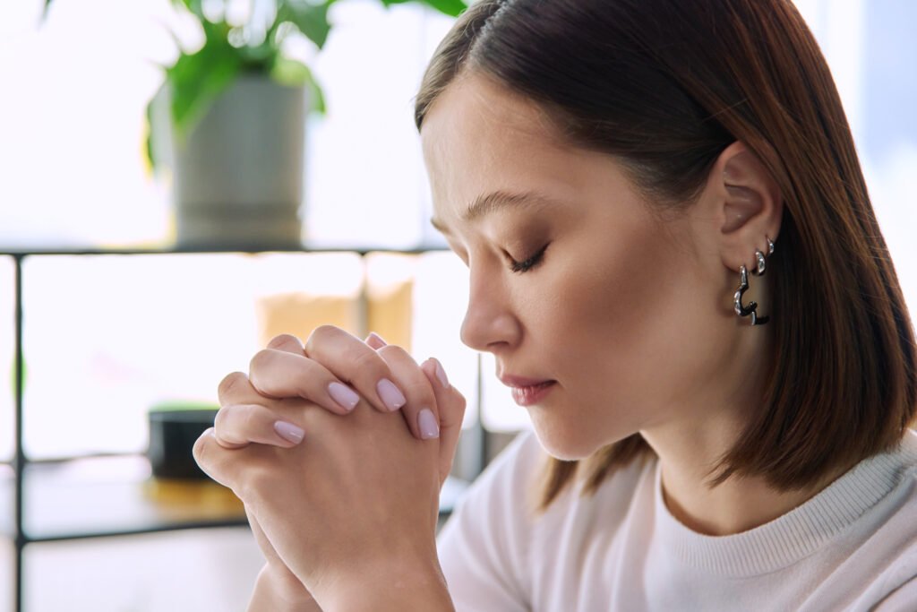 Excited sad upset young woman with folded hands, face in profile close-up